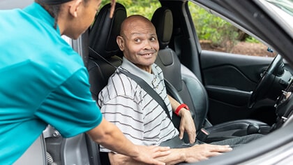 caregiver helping senior male with transportation services