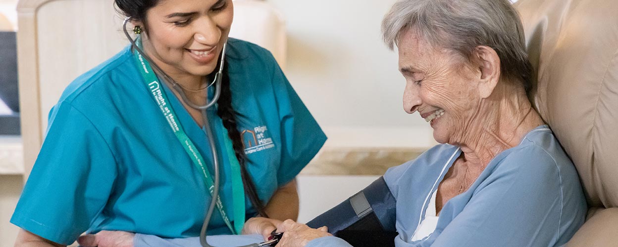 female caregiver taking blood pressure of senior woman