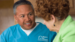 A caregiver in blue smiles at his client.