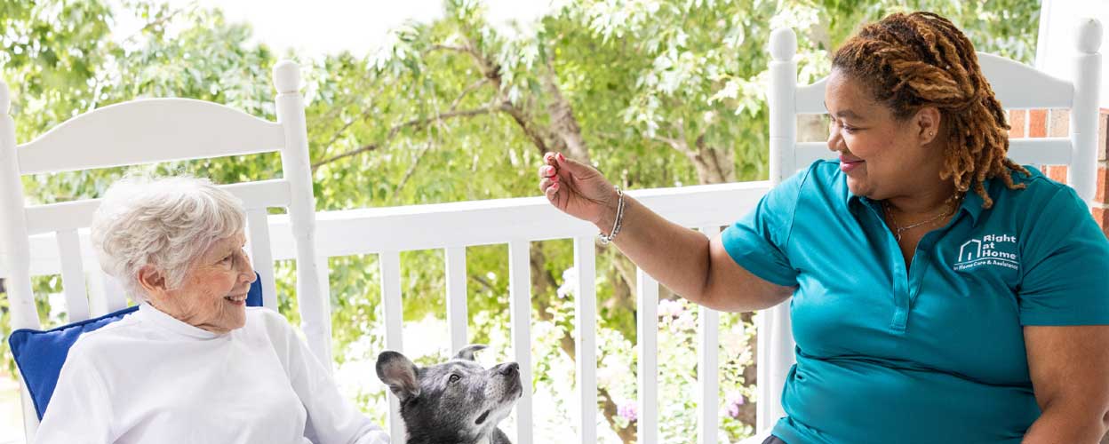 senior woman and caregiver giving high five on porch