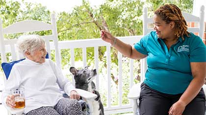 senior woman and caregiver giving high five on porch