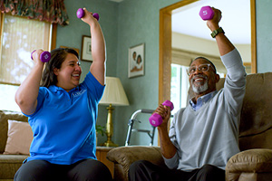 Caregiving and senior exercising while sitting down