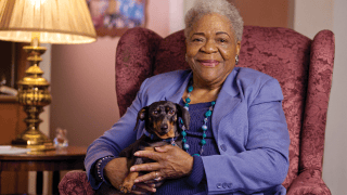 An elderly woman sitting comfortably with a dog on a single sofa chair